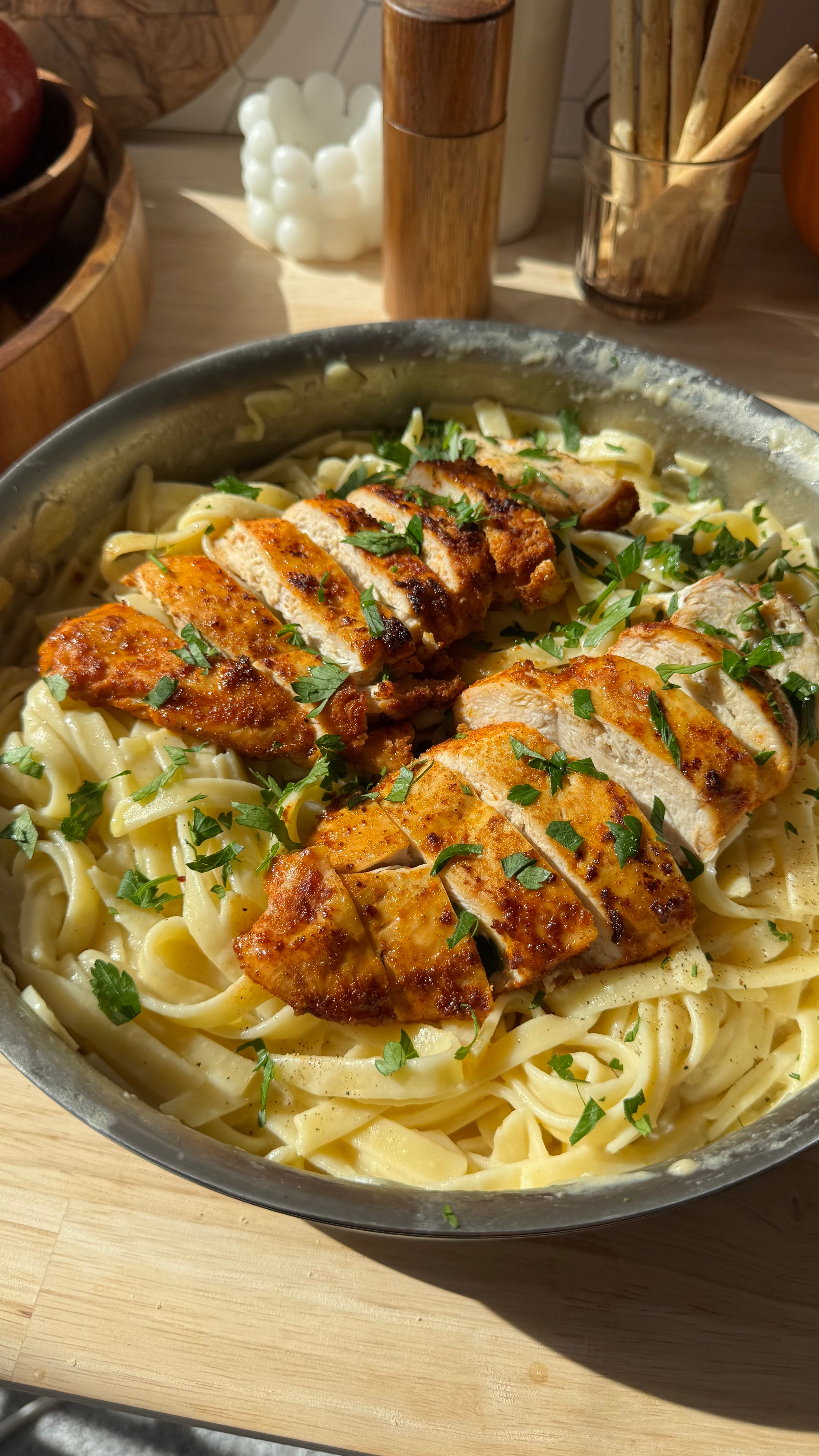 Fettuccine pasta with chicken and herbs in a pan on a wooden surface