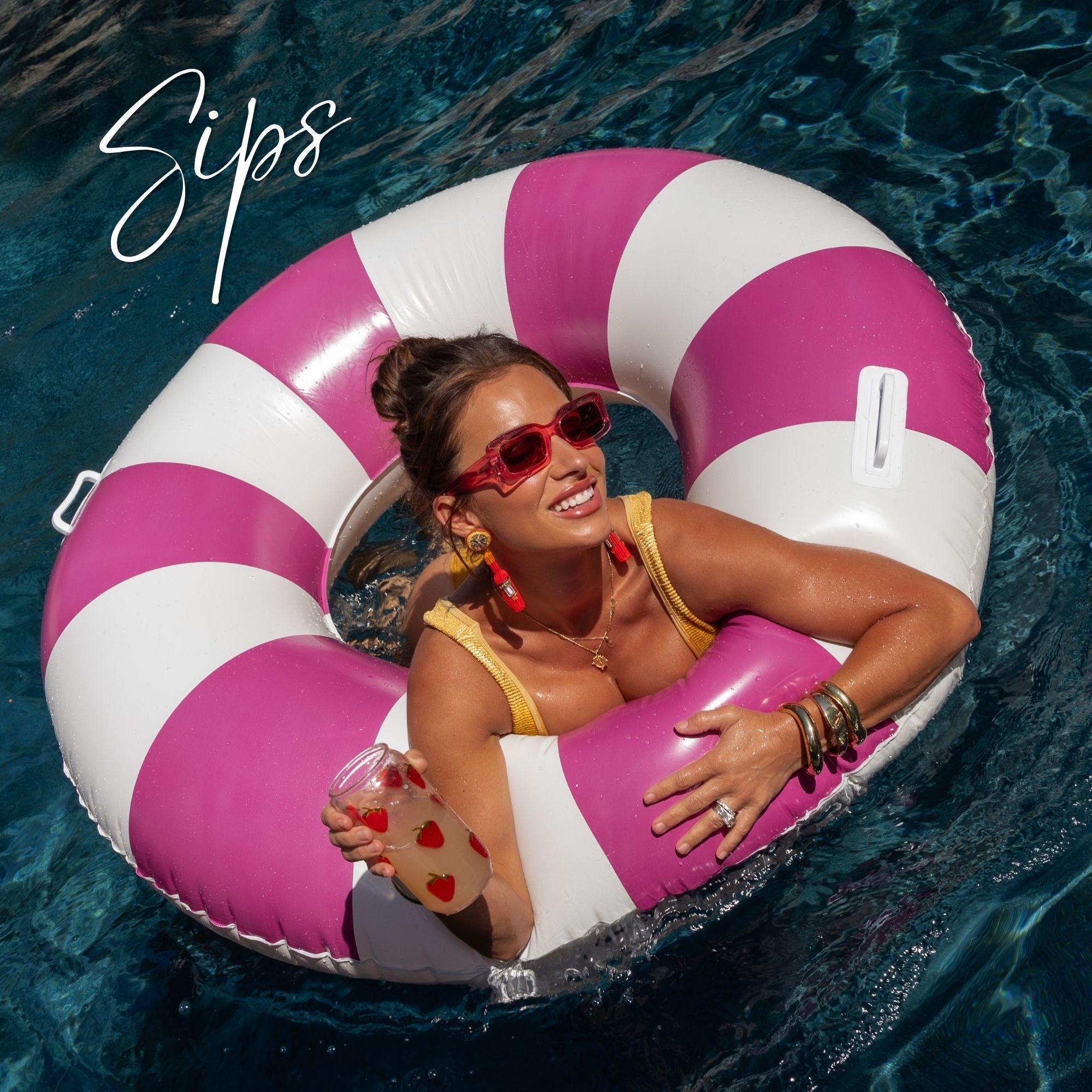 Jessie wearing red sunglasses and a yellow bikini floats in a pink and white striped pool float on blue water, holding a drink with red hearts. The word 'Sips' is written in white script in the top left corner.